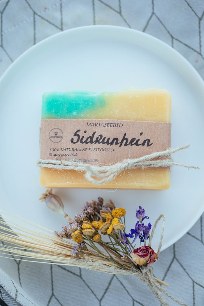 Close-up of a handmade natural bar soap with floral accents on a ceramic plate.
