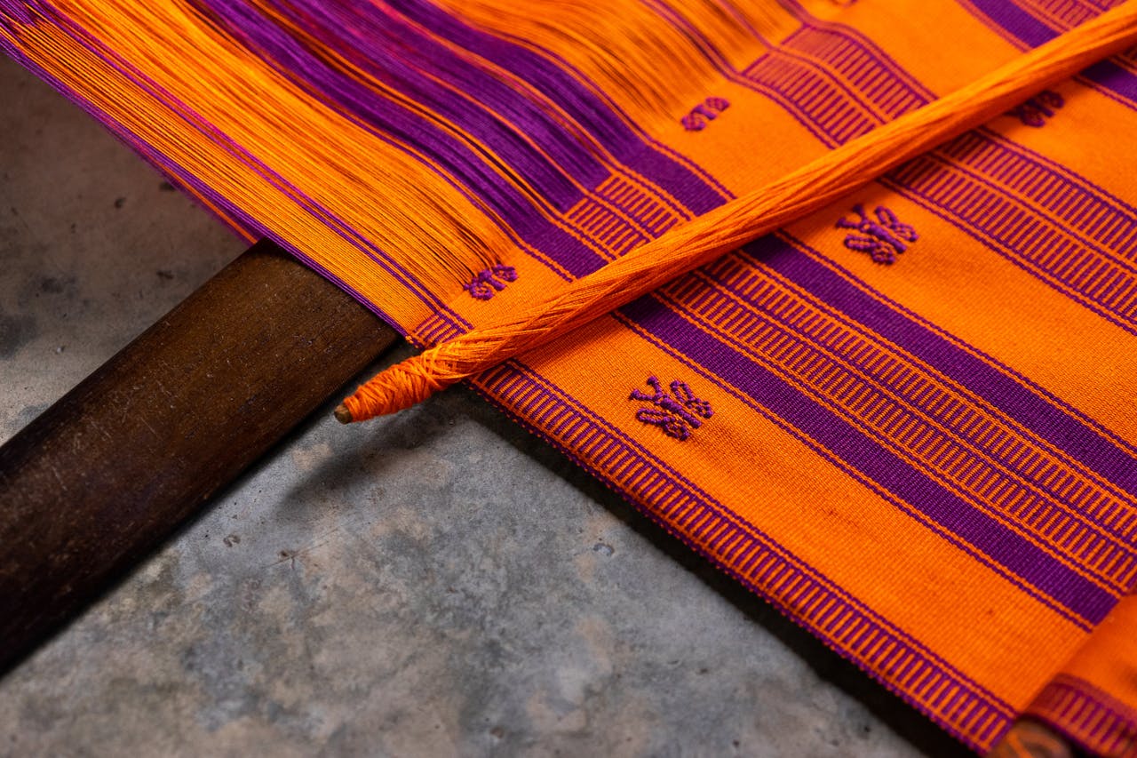 Close-up of a colorful handwoven Mexican textile in orange and purple hues.